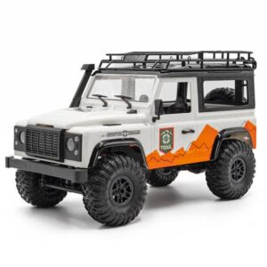A three-quarter view studio photograph of a white scale-model RC rock crawler. The Land Rover Defender-style vehicle has a black roof rack, side snorkel, deep-tread off-road tires, and distinctive orange geometric graphics on the side with a "TRAIL" logo.